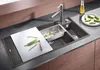 A modern kitchen sink with a cutting board and vegetables being prepared. Náhled obrázku produktu