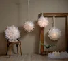 Several white paper star lanterns are displayed in a room with a wooden frame and candles in the foreground. Podgląd zdjęcia produktu