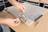 A person is using a jig and a hinge to mark a cabinet door for drilling. Voir les images du produit