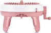 A side view of a pink and white knitting machine with four legs and a crank on the side. Náhled obrázku produktu
