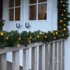 A garland with lights is draped over a wooden railing in front of a white door. Produktbild-Vorschau