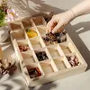 A hand is placing a leopard print hair claw into a wooden organizer with multiple compartments, which contains various hair accessories. Produktbild-Vorschau