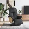 A black faux leather recliner chair with wooden accents is placed on a gray rug in a living room setting. A large plant is to the left of the chair, and a TV stand with a TV is visible in the background. Produktbild-Vorschau