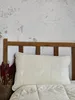 A pillow and duvet on a bed with a wooden headboard against a textured wall. Anteprima dell’immagine prodotto