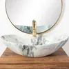 A marble basin sink with a gold faucet sits on a wooden countertop, with a round mirror reflecting the scene. Anteprima dell’immagine prodotto