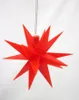 A red star-shaped Christmas ornament hangs against a white background. Produktbild-Vorschau