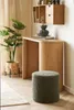 A green pouf sits in front of a wooden desk with a plant and vase on top. Produktbild-Vorschau