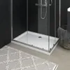 A close-up view of a white shower tray with a textured surface, part of a modern shower enclosure. A grey rug is in the foreground, and a woven basket with a towel is visible to the right. Náhľad obrázku produktu