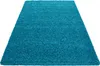 A high-pile, turquoise rug is shown from a diagonal, slightly elevated angle against a white background.