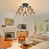 A living room with a fireplace, sofa, chairs, and a coffee table, featuring a ceiling light. Produktbild-Vorschau