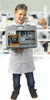 A young boy in a lab coat and goggles holds a microscope kit in a laboratory setting. Produktbild-Vorschau