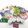 A collection of food packaging and cans, along with a credit card, arranged on a white surface. Produktbild-Vorschau