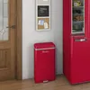 A red retro-style trash can is placed next to a red refrigerator and a wooden door. A small bulletin board with notes is on the wall above the trash can. Voir les images du produit