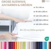 A hand is shown smoothing a white sheet over a mattress, with text and size options listed on the right. A row of colored fabric swatches is at the bottom. Produktbild-Vorschau