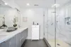 A modern bathroom with a double vanity, a large mirror, and a glass-enclosed shower. Náhled obrázku produktu