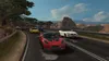 A group of sports cars racing on a winding road with a mountainous landscape in the background. Produktbild-Vorschau