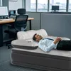 A man is lying on an inflatable mattress in an office setting. Náhled obrázku produktu