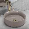 A close-up view of a beige round vessel sink with a gold drain and a gold faucet. Náhľad obrázku produktu