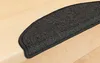 A close-up shot of a dark gray, half-round stair mat placed on a light-colored wooden step. Produktbild-Vorschau