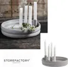 A grey ceramic candle holder with four white candles and some small white flowers on a dark wooden surface. Produktbild-Vorschau