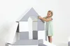 A young girl is playing with a set of soft foam blocks, building a structure that resembles a house. Produktbild-Vorschau