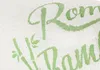 A close-up of a textured white fabric with green embroidered text and a floral/leaf design. Produktbild-Vorschau
