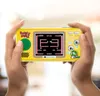Hands holding a yellow portable gaming console displaying the Bubble Bobble game. Náhled obrázku produktu