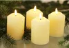 Four cream-colored LED candles are arranged with pine branches in the foreground and background. Produktbild-Vorschau