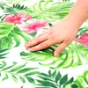 A hand touching a picnic blanket with a floral pattern. Náhled obrázku produktu