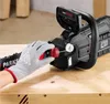 A gloved hand is shown adjusting a red cap on a black electric chainsaw, which is resting on a wooden surface. Produktbild-Vorschau