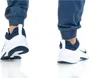 A close-up view of a person's feet wearing Nike shoes and blue pants. Voir les images du produit