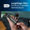 A person is holding a gray electric trimmer and plugging it in. The background is blurred. Produktbild-Vorschau