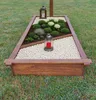 A wooden grave frame filled with plants and white stones, with two lanterns placed on it. Anteprima dell’immagine prodotto