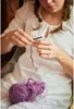 A person is crocheting with purple yarn. Podgląd zdjęcia produktu