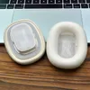 Two white ear pads for headphones are placed on a wooden surface in front of a laptop keyboard. Podgląd zdjęcia produktu
