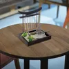 A small Zen garden with a Buddha statue and wind chimes sits on a wooden table. Anteprima dell’immagine prodotto