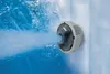 A close-up shot of a jet in a hot tub, spraying water. Produktbild-Vorschau