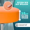 Close-up of an orange stool seat with text overlays highlighting its features, including a finger pressing into the cushion and a measurement of the extra thick padding. Produktbild-Vorschau