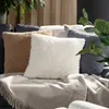 Several fluffy throw pillows are arranged on a couch with a blanket. Voir les images du produit