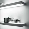 A modern kitchen shelf with integrated LED lighting, displaying two stainless steel pots. Produktbild-Vorschau