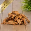 A pile of dried chicken necks on a wooden surface, with a green plant in the background. Produktbild-Vorschau