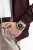 A person's hand with a watch is placed in the pocket of their pants. Produktbild-Vorschau