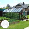 A greenhouse filled with plants, situated in a garden next to a house. Náhled obrázku produktu
