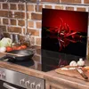 A kitchen scene with a glass cutting board featuring red chili peppers, a stove, and various kitchen items. Náhled obrázku produktu