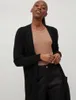 A woman wearing a black cardigan and a tan top. Produktbild-Vorschau