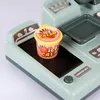 A close-up of a toy cash register with an ice cream cup on the conveyor belt. Produktbild-Vorschau