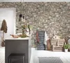 A kitchen island with a stone-patterned wallpaper background, featuring decorative items and a chalkboard menu. Produktbild-Vorschau