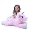 A young girl is sitting behind a large, plush pink unicorn. Produktbild-Vorschau