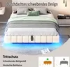 A bed with a beige upholstered frame and blue LED lighting underneath, set in a bedroom with a nightstand and a wall-mounted shelf. Náhľad obrázku produktu