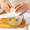 Hands cracking an egg over an egg separator into a glass bowl. Produktbild-Vorschau